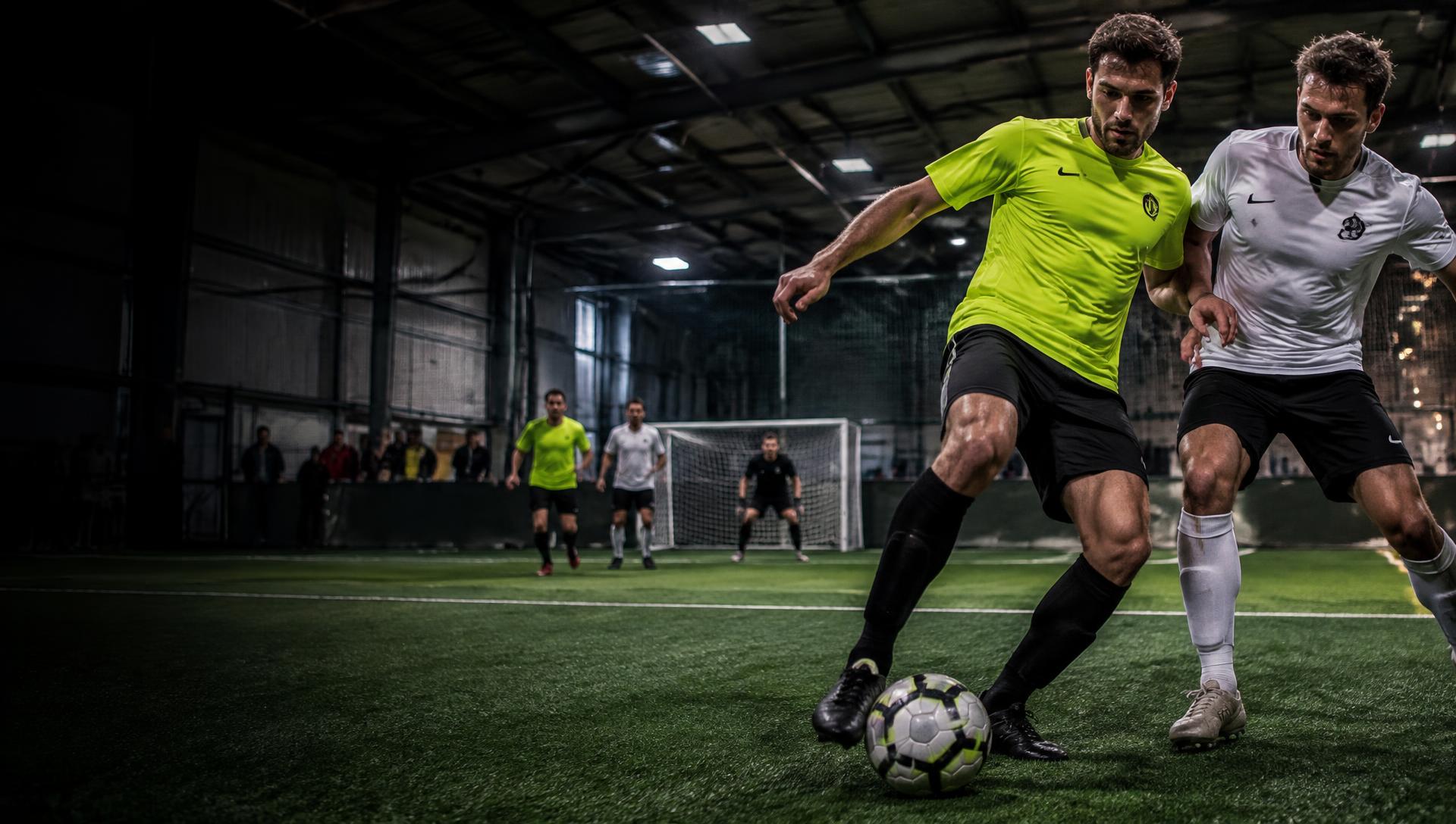 Fußballspieler im Zweikampf auf einem Indoor-Kunstrasen-Court